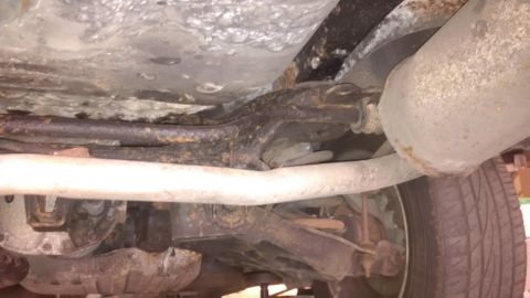 1994 Ford Thunderbird - The undercarriage of a vehicle displays significant rust and corrosion on its components.