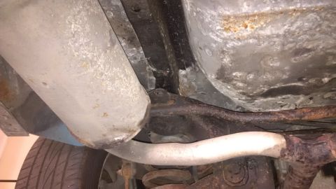 1994 Ford Thunderbird - Undercarriage view of a vehicle, highlighting exhaust components and a tire, with visible signs of rust and undersealing.