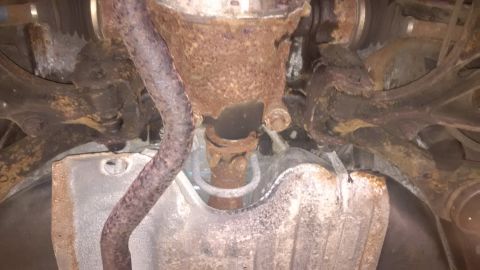 1994 Ford Thunderbird - The underside of a vehicle shows significant rust on the exhaust system and suspension components.