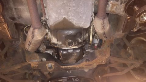 1994 Ford Thunderbird - Underside view of vehicle transmission and exhaust system, showing rust and oil leaks.