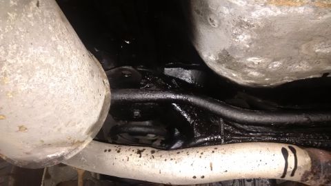 1994 Ford Thunderbird - Undercarriage view showing exhaust pipes and suspension components that have been treated with black undercoating for rust repair.