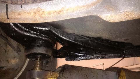 1994 Ford Thunderbird - Undercarriage view shows black undercoating on the frame and suspension parts, with a jack visible.