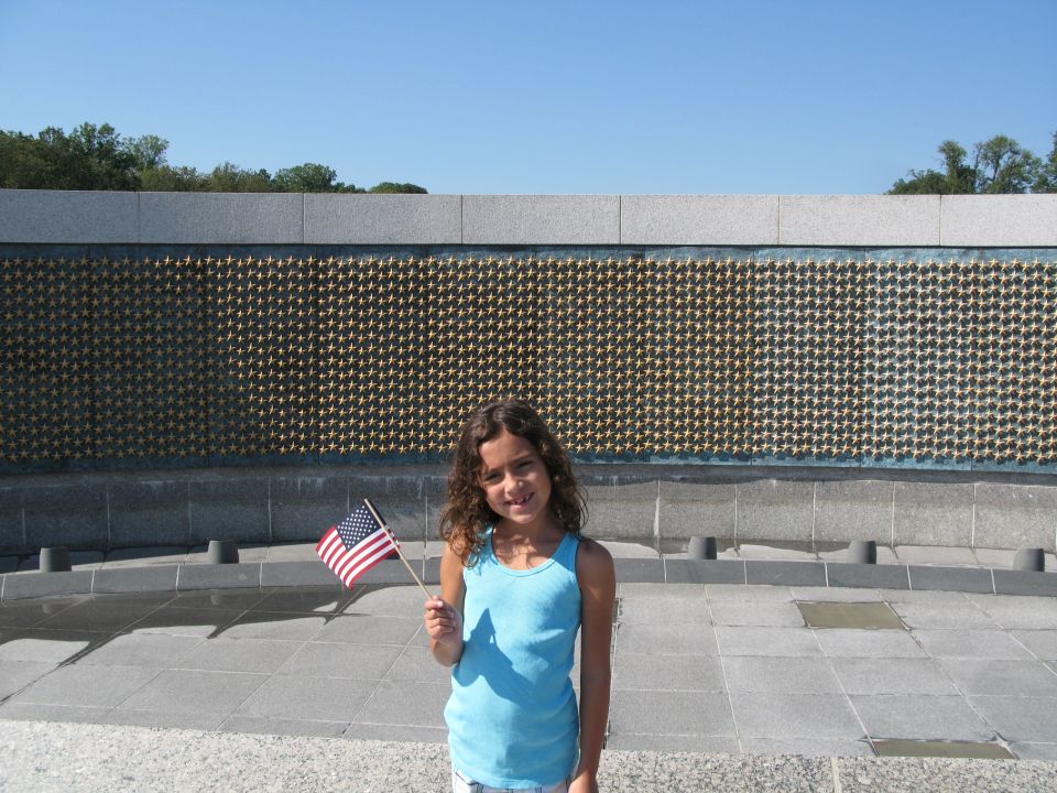 Girl with American flag stands before a wall of stars