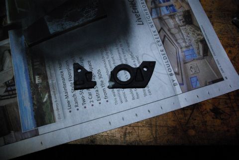 1995 Ford Bronco - Two black plastic car parts are shown on top of a newspaper.