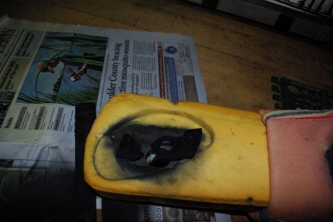 1995 Ford Bronco - Close-up of car seat foam and a black plastic part, placed on top of a newspaper.