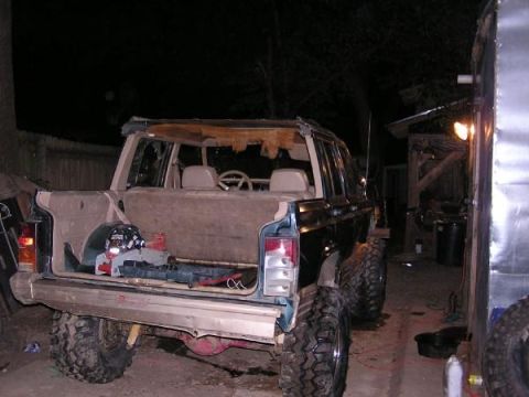 Jeep Cherokee XJ with open tailgate, showing interior and cargo area. Modified suspension and large tires are