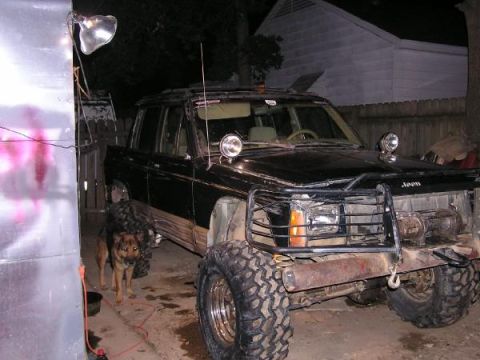 Black Jeep Comanche pickup truck with large tires and a brush guard