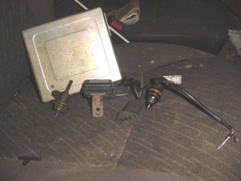 1992 Ford Bronco - Engine control unit and fuel injectors are laid out on a car seat.