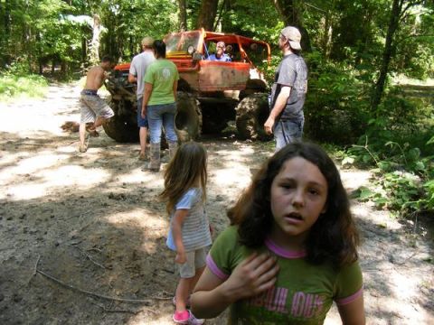 Orange off-road buggy with people gathered around in a wooded area
