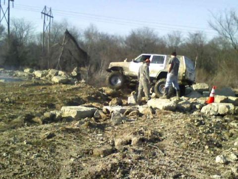 White SUV with two people navigating a rocky obstacle course