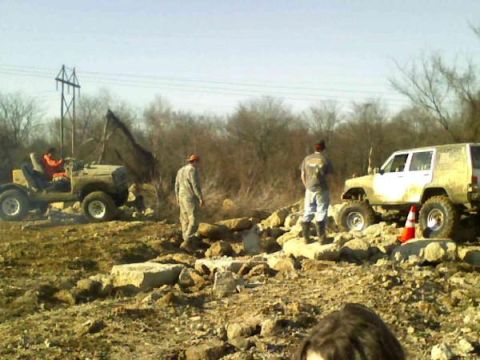 Off-road vehicles navigating a rocky terrain with three people present