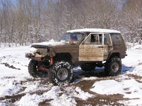 Muddy Jeep Cherokee XJ with lifted suspension and large tires in the snow