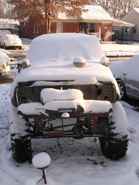 Snow-covered off-road vehicle front view with exposed grille and suspension
