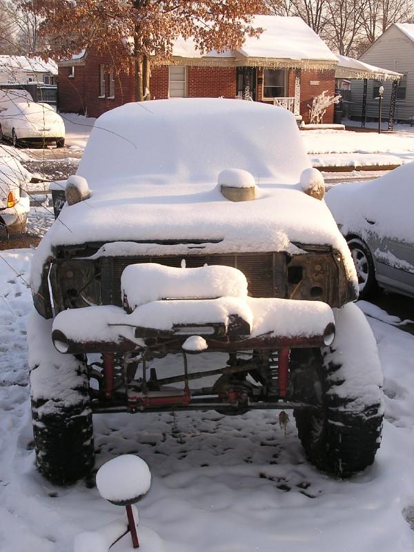 Snow-covered off-road vehicle front view with exposed grille and suspension