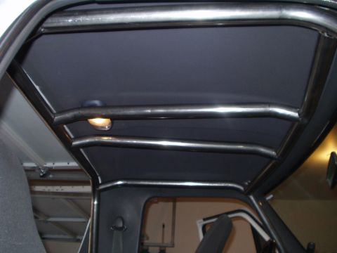 1993 Ford Bronco - The interior of a vehicle shows a custom roll cage structure, obscuring the original headliner.