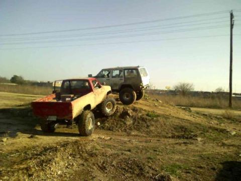 Red pickup truck and white SUV on a dirt hill