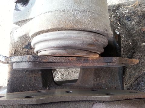 1981 Ford Bronco - A close-up view shows a worn suspension bellows resting on a metal mounting plate, with visible SuperMotors branding at the bottom right.