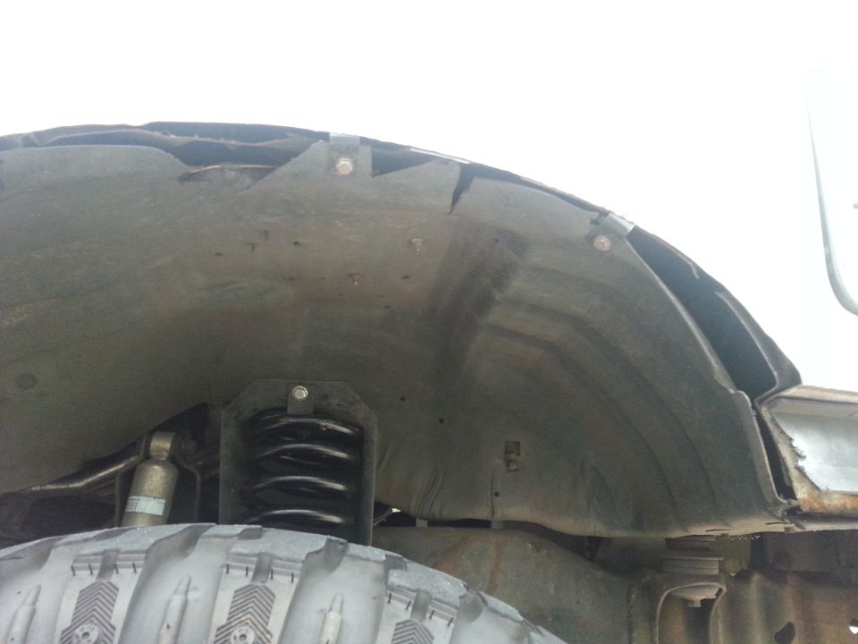 Inner fender well and suspension components of a vehicle, showing modifications and rust
