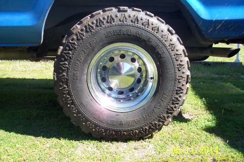 1978 Ford Bronco - This photo shows a close-up of a Super Swamper tire and chrome wheel on a blue vehicle.