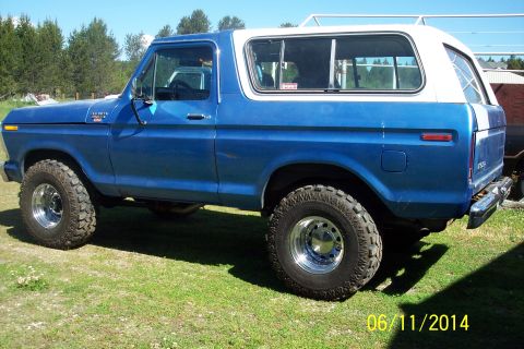 1978 Ford Bronco - Side view of a blue 1978 Ford Bronco with a white hardtop, showing its tires and chrome wheels.