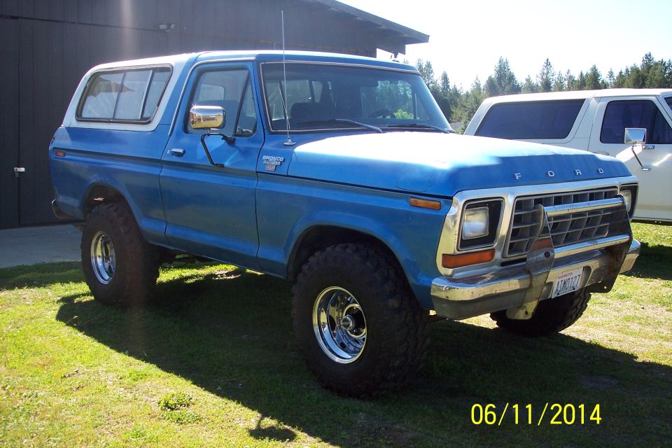 Blue 1978 Ford Bronco with a white removable top, parked on grass, 3/4 front view