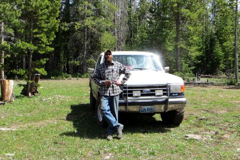 1989 Ford Bronco - A man poses with his white Ford pickup truck in a forest clearing.