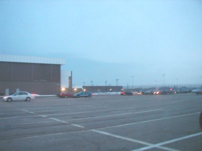 1997 Ford Taurus - A wide shot of a parking lot with multiple vehicles and a large building in the background.