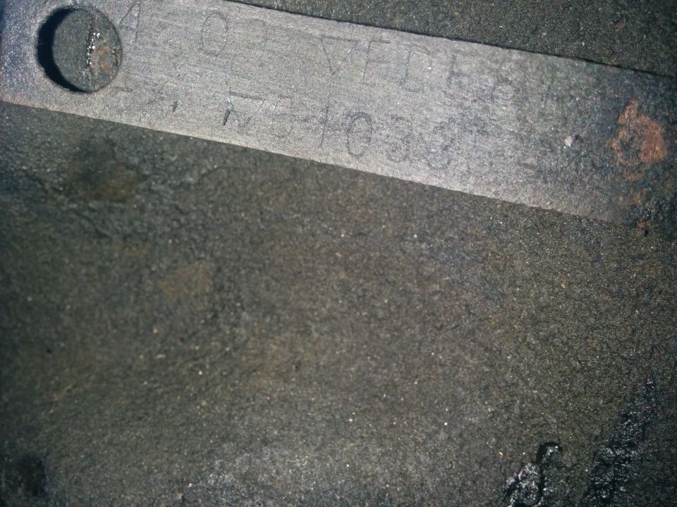 Metal plate with stamped numbers and letters, possibly a VIN or part number