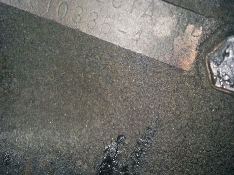 1988 Ford Bronco - A close-up view of a stamped metal identification plate on a dirty surface.