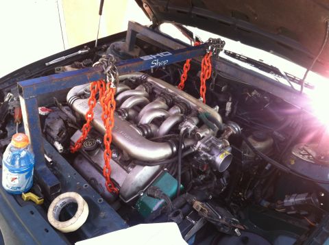 1993 Ford Taurus - The engine is suspended by an engine hoist, ready for removal from the vehicle.