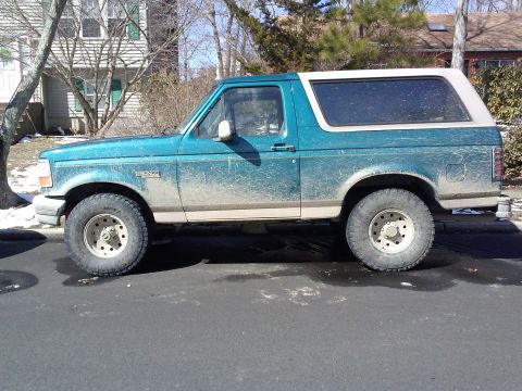 1996 Ford Bronco - A teal 1996 Ford Bronco is shown from the side, parked on a residential street.