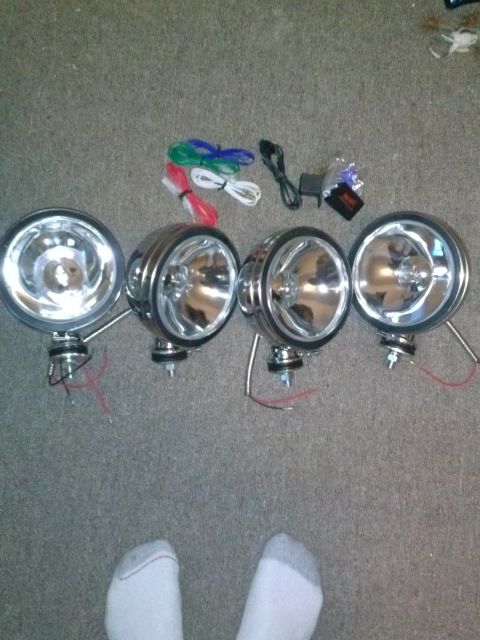 1996 Ford Bronco - A set of four chrome fog lights, complete with wiring and mounting hardware, laid out on a carpeted surface.