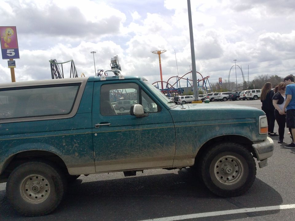 Side view of a green 1996 Ford Bronco with a light-colored roof and aftermarket lights