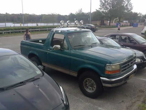 1996 Ford Bronco - This green Ford Bronco is parked in a lot near a body of water.