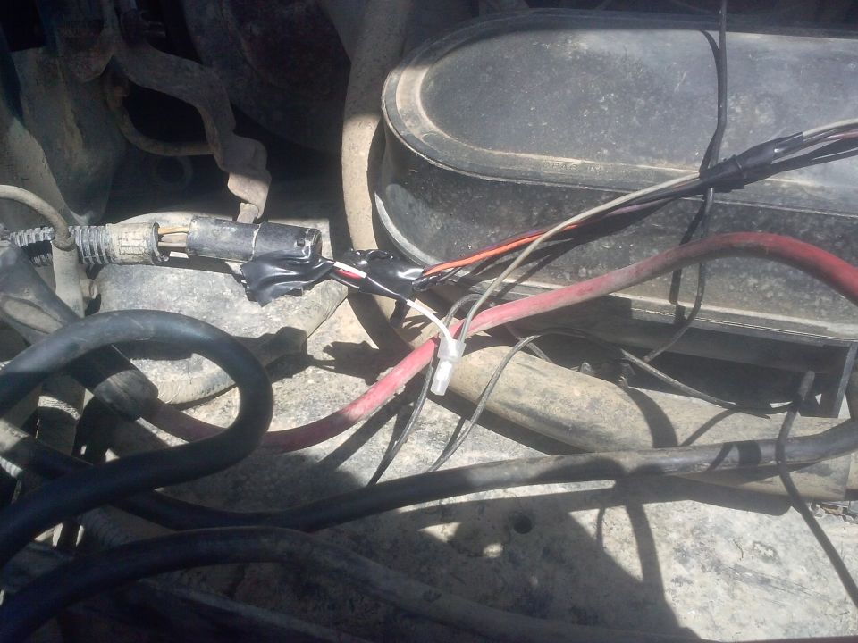 Close-up of engine bay wiring with black electrical tape repairs