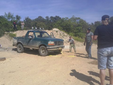 1996 Ford Bronco - A green Ford Bronco is parked on a dirt lot, with several people standing nearby.
