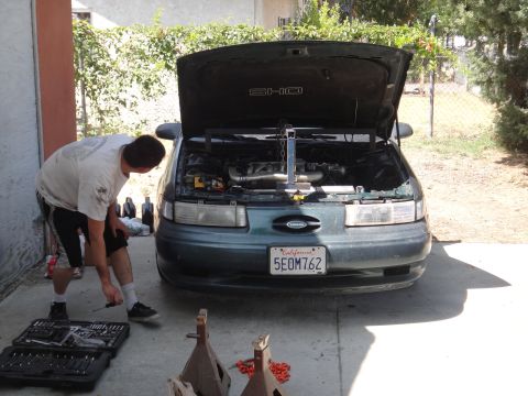 1993 Ford Taurus - A person works on the engine of a 1993 Ford Taurus SHO in a driveway.