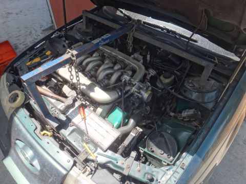 1993 Ford Taurus - Engine bay of a 1993 Ford Taurus, equipped with an engine hoist and various tools.