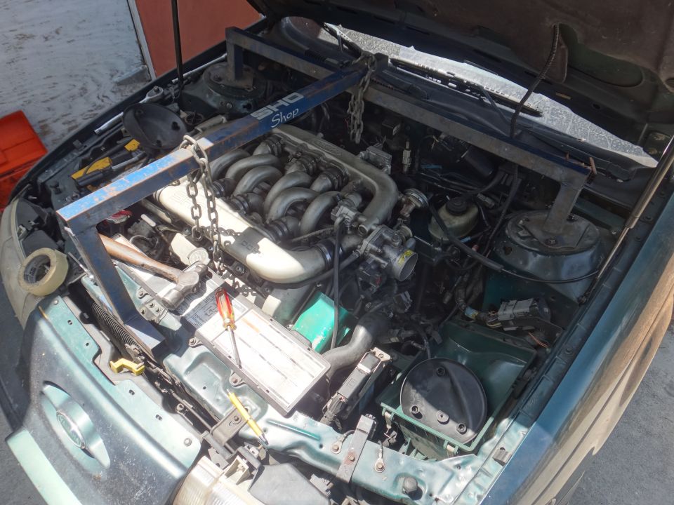 Green 1993 Ford Taurus engine bay with engine hoist, tools, and V6 engine