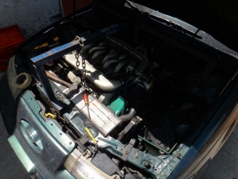 1993 Ford Taurus - Engine bay of a 1993 Ford Taurus, a V6 engine and an engine hoist.