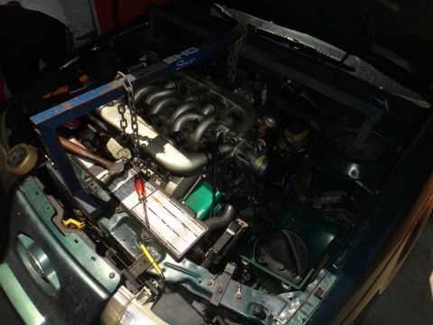 1993 Ford Taurus - The engine is being worked on, supported by an engine hoist. Tools are laid out nearby for the repair.