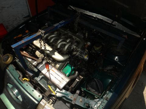 1993 Ford Taurus - Engine bay of a 1993 Ford Taurus, showing the V6 engine and an engine hoist in place for service.
