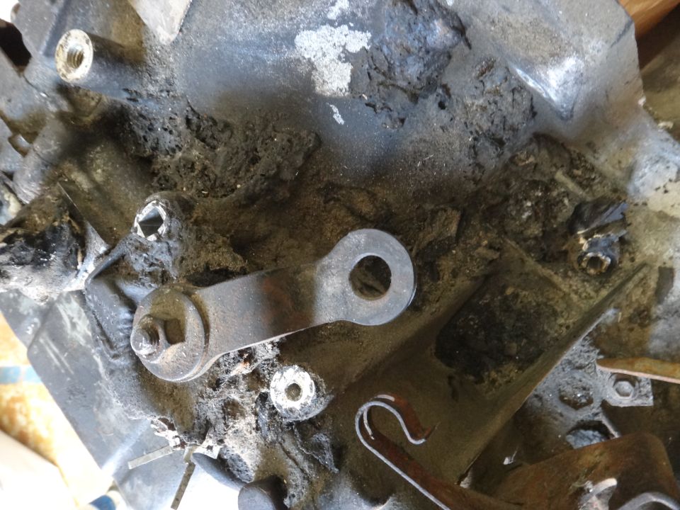 Close-up of a metal linkage attached to a dirty engine component