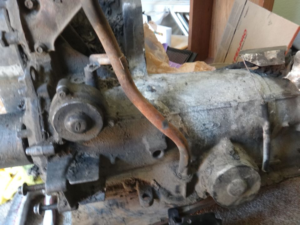 close-up of dirty engine block and transmission with a rusty pipe running over it