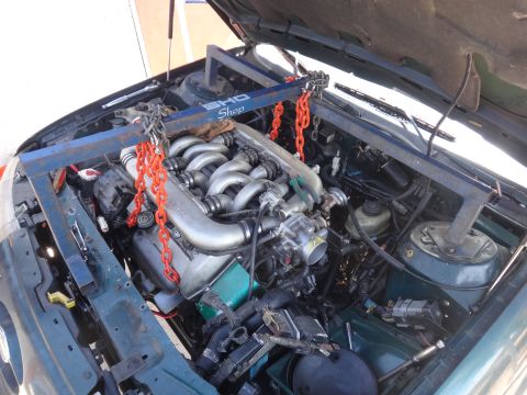 1993 Ford Taurus - The engine of a 1993 Ford Taurus is hoisted out of the engine bay using a shop crane for maintenance.