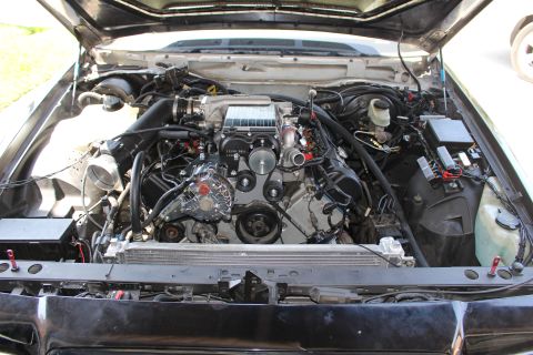 2003 Ford Crown Victoria - Front-facing view into an engine bay with a Kenne Bell supercharger, intake plumbing and the exposed radiator core support.