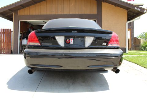 2003 Ford Crown Victoria - Straight rear view of a black sedan with a Ford oval, MARAUDER trunk badge, dual exhaust and an emblem decklid.
