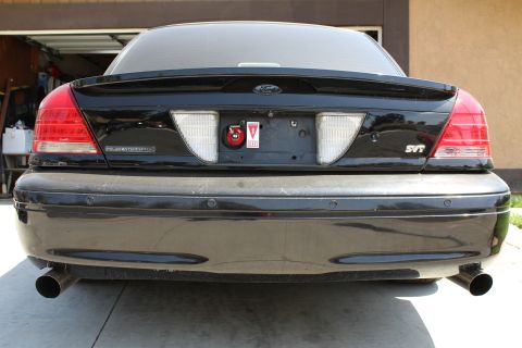 2003 Ford Crown Victoria - Rear view of a black sedan wearing Ford oval, POLICE INTERCEPTOR and SVT badges with dual exhaust tips.