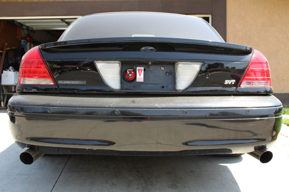 Rear of a black sedan badged Police Interceptor and SVT with dual exhaust