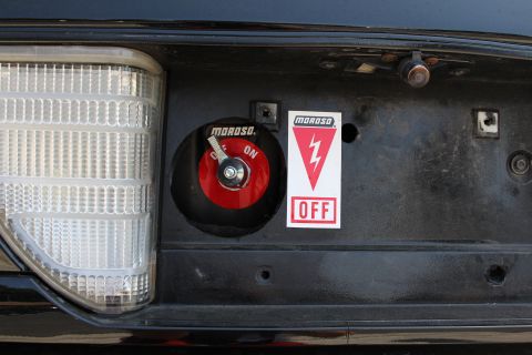 2003 Ford Crown Victoria - Detail of a red Moroso master battery disconnect switch beside its red and white ON/OFF decal on a black rear panel.